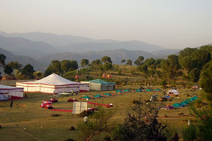 Event tents and camp laid out below pine-covered hills